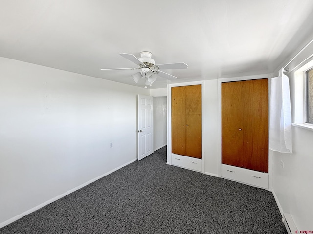 135 N 4th St, Hotchkiss, CO 81419 - unfurnished bedroom featuring dark colored carpet, baseboards, multiple closets, and a ceiling fan