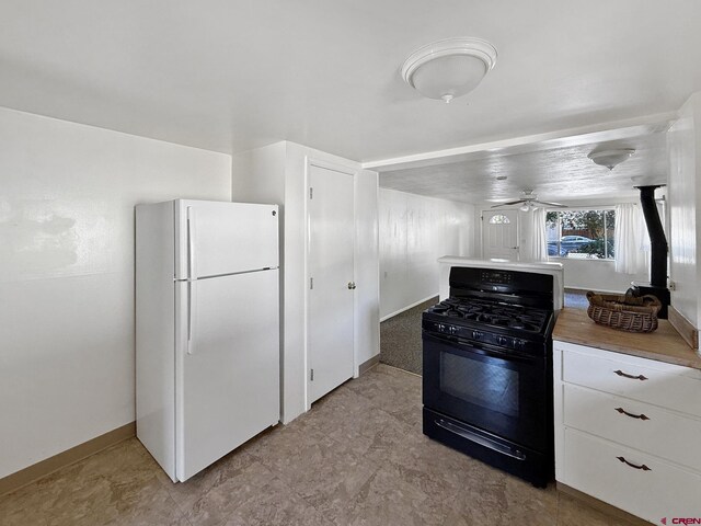 135 N 4th St, Hotchkiss, CO 81419 - kitchen with freestanding refrigerator, black gas stove, baseboards, ceiling fan, and white cabinetry