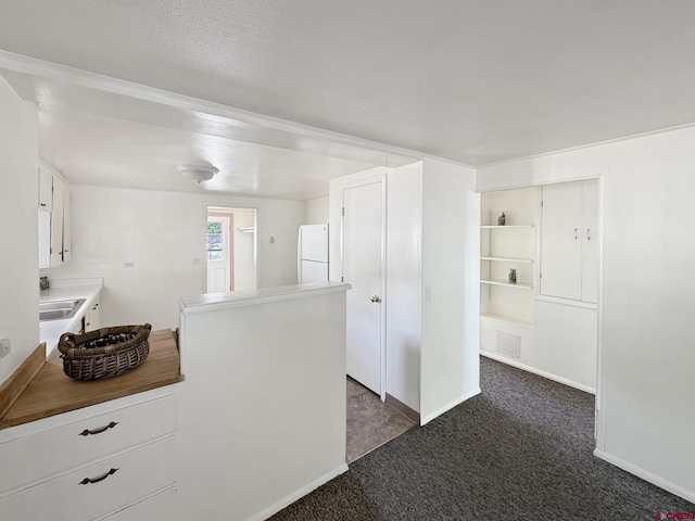 135 N 4th St, Hotchkiss, CO 81419 - kitchen featuring freestanding refrigerator, dark carpet, white cabinets, a sink, and baseboards