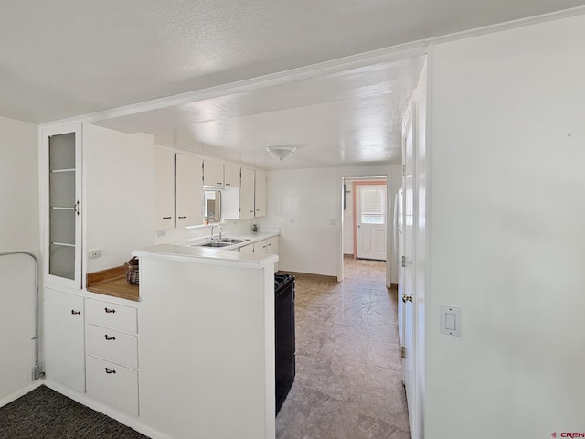 135 N 4th St, Hotchkiss, CO 81419 - kitchen featuring a sink, white cabinets, light countertops, a peninsula, and baseboards