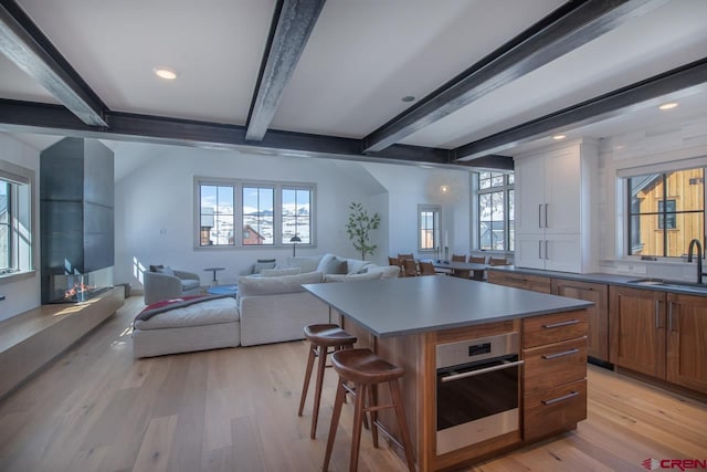 918 Belleview Ave, Crested Butte, CO 81224 - kitchen with a sink, beam ceiling, light wood finished floors, a kitchen breakfast bar, and oven