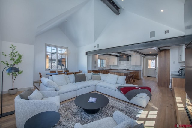 918 Belleview Ave, Crested Butte, CO 81224 - living area featuring wood finished floors, high vaulted ceiling, beam ceiling, healthy amount of natural light, and baseboards
