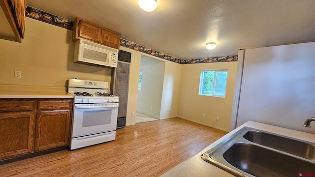 1551 G86 Rd, Delta, CO 81416 - kitchen with white appliances, a sink, light wood finished floors, brown cabinetry, and light countertops