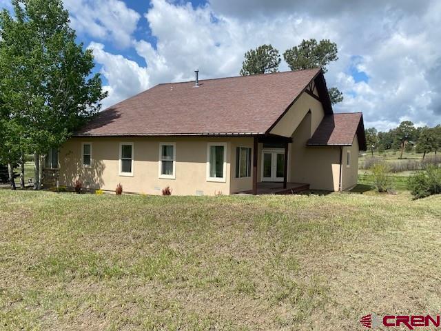 196 Dylan Dr, Pagosa Springs, CO 81147 - rear view of house featuring french doors, a lawn, stucco siding, and a shingled roof