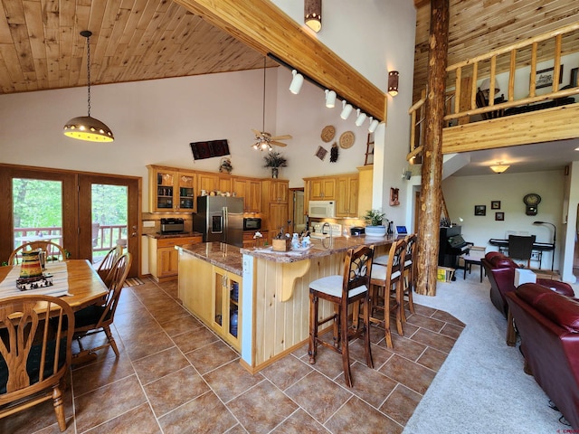 421 Elk Meadow Run, Antonito, CO 81120 - kitchen featuring stainless steel fridge, high vaulted ceiling, white microwave, glass insert cabinets, and stone counters