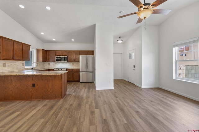 1602 S Taylor Cir, Bayfield, CO 81122 - kitchen featuring stainless steel appliances, a peninsula, backsplash, light wood finished floors, and brown cabinets