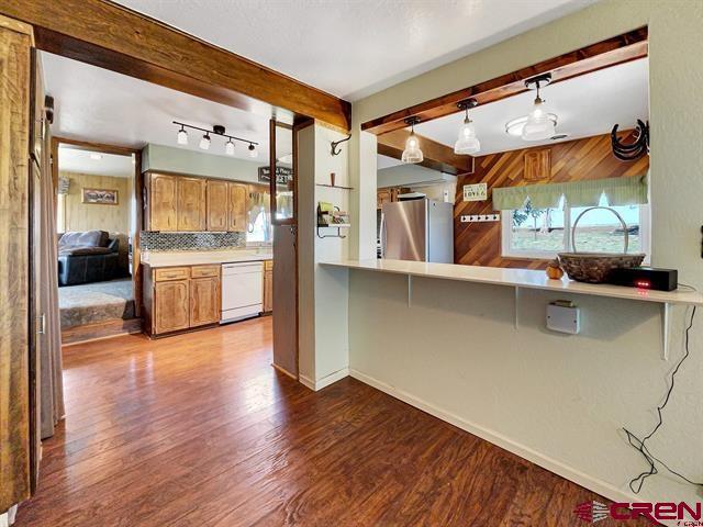 14702 Rd 14, Cahone, CO 81320 - kitchen with freestanding refrigerator, dishwasher, wood finished floors, decorative backsplash, and beamed ceiling