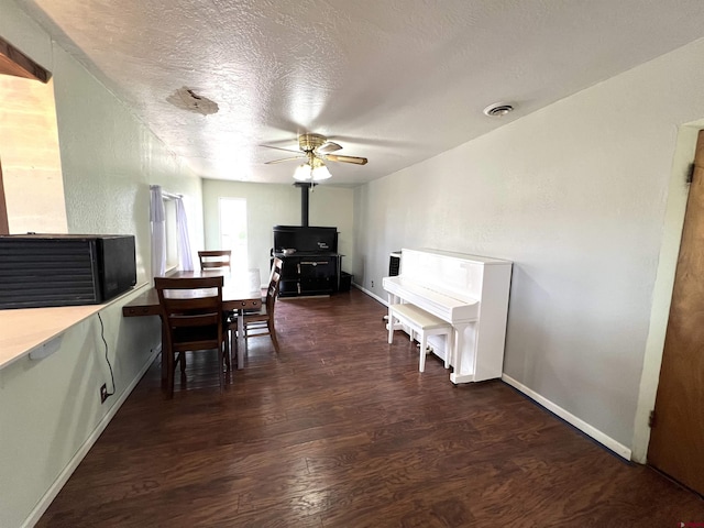 14702 Rd 14, Cahone, CO 81320 - dining room with dark wood-style floors, a ceiling fan, baseboards, a wood stove, and a textured ceiling