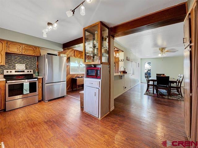 14702 Rd 14, Cahone, CO 81320 - kitchen featuring stainless steel appliances, wood finished floors, glass insert cabinets, decorative backsplash, and a ceiling fan