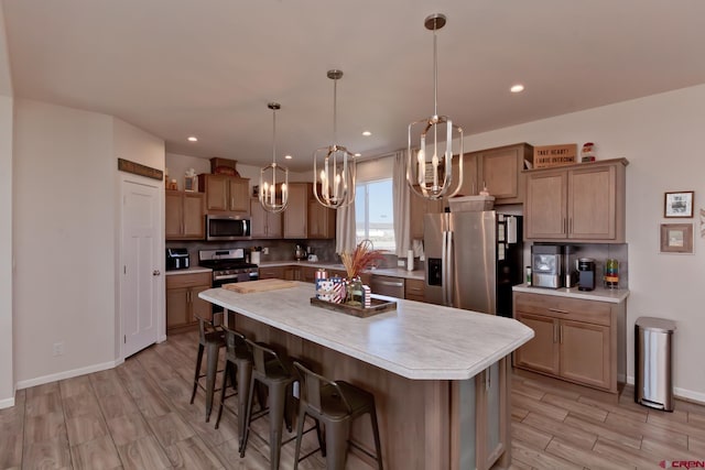 729 Spotted Pony Ct, Delta, CO 81416 - kitchen with appliances with stainless steel finishes, a chandelier, light countertops, a kitchen island, and light wood finished floors