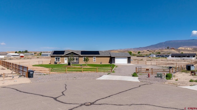 729 Spotted Pony Ct, Delta, CO 81416 - ranch-style house with gravel driveway, roof mounted solar panels, a mountain view, and a garage