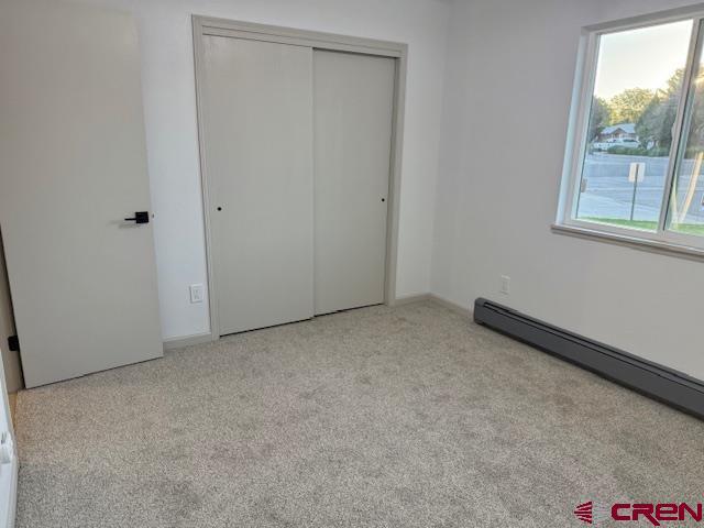 2149 Hartord Way Unit A, Montrose, CO 81401 - unfurnished bedroom featuring carpet, a closet, a baseboard heating unit, and baseboards