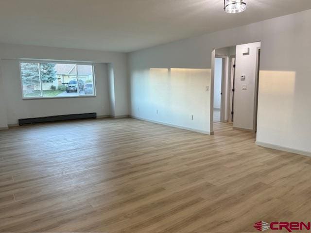 2149 Hartord Way Unit A, Montrose, CO 81401 - empty room featuring a baseboard radiator, light wood-style flooring, and baseboards