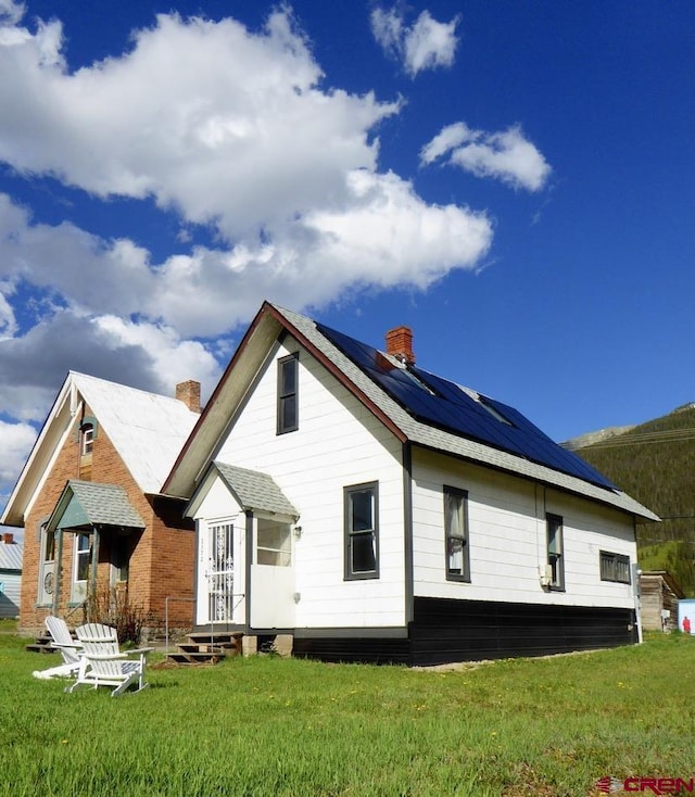 1572 Greene St, Silverton, CO 81433 - rear view of property with roof mounted solar panels, a lawn, and a chimney