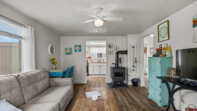 355 NW 5th St, Cedaredge, CO 81413 - living area featuring a wood stove, a ceiling fan, dark wood-type flooring, and baseboards
