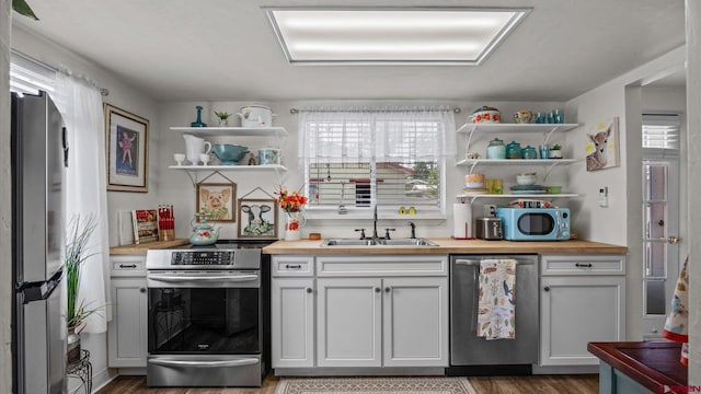 355 NW 5th St, Cedaredge, CO 81413 - kitchen with appliances with stainless steel finishes, open shelves, a sink, butcher block countertops, and wood finished floors