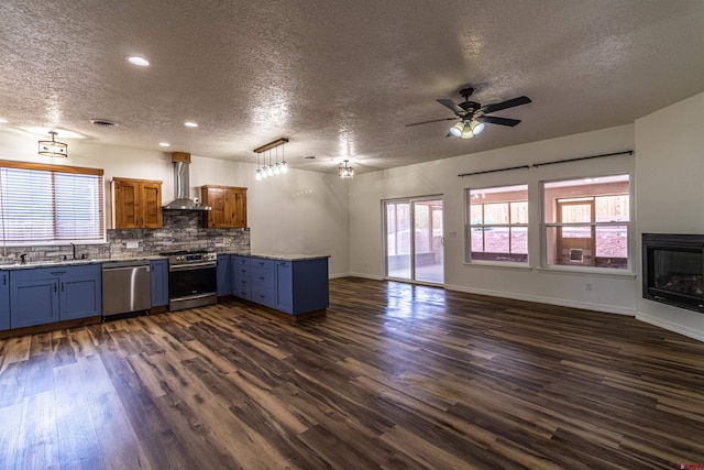 1043 Valley View Dr, Bloomfield, NM 87413 - kitchen with stainless steel appliances, a textured ceiling, a peninsula, wall chimney range hood, and blue cabinetry