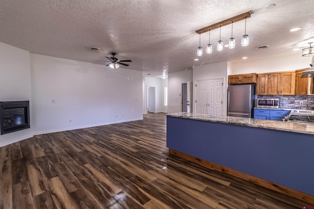 1043 Valley View Dr, Bloomfield, NM 87413 - kitchen featuring appliances with stainless steel finishes, a textured ceiling, dark wood-style flooring, a ceiling fan, and brown cabinetry