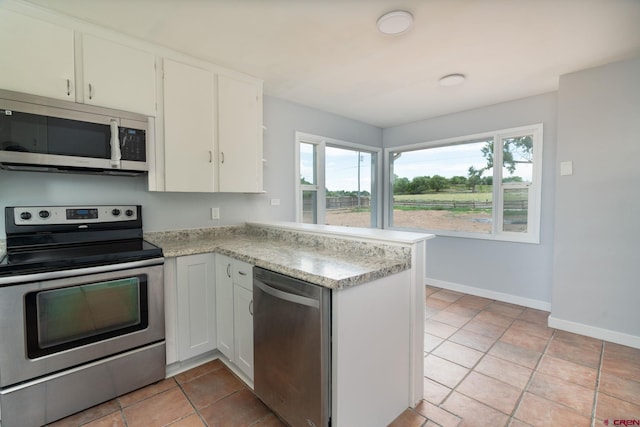 6038 Townsend Rd, Delta, CO 81416 - kitchen with appliances with stainless steel finishes, light countertops, a peninsula, white cabinets, and light tile patterned floors