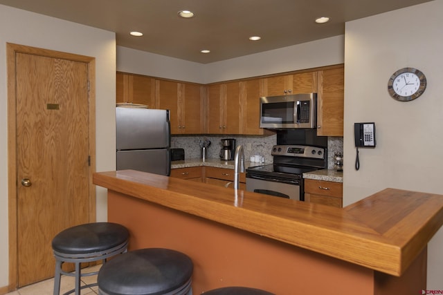 93 Needles Way Unit 413, Durango, CO 81301 - kitchen featuring appliances with stainless steel finishes, brown cabinets, recessed lighting, and tasteful backsplash