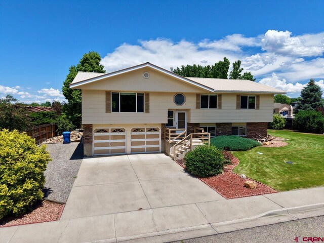 2343 Oldham Way, Montrose, CO 81401 - raised ranch featuring a garage, concrete driveway, brick siding, and a metal roof