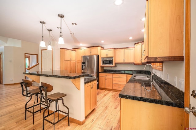95 Ute Pass W, Durango, CO 81301 - kitchen featuring appliances with stainless steel finishes, light brown cabinets, a kitchen breakfast bar, light wood-style flooring, and pendant lighting