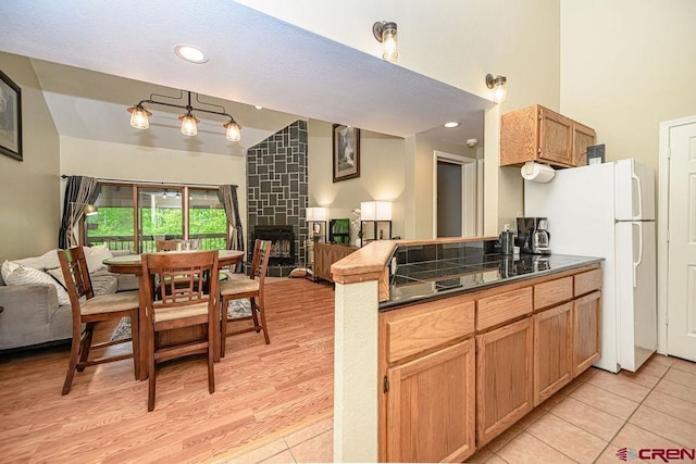 166 Yankee Girl Ct Unit 313, Durango, CO 81301 - kitchen with open floor plan, dark countertops, a fireplace, light tile patterned floors, and high vaulted ceiling