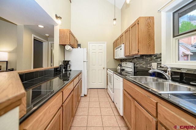 166 Yankee Girl Ct Unit 313, Durango, CO 81301 - kitchen featuring a towering ceiling, white appliances, light tile patterned floors, tasteful backsplash, and dark countertops