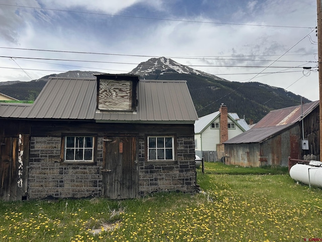 1250 Snowden St, Silverton, CO 81433 - view of front facade featuring stone siding, a metal roof, a front lawn, a mountain view, and an outbuilding