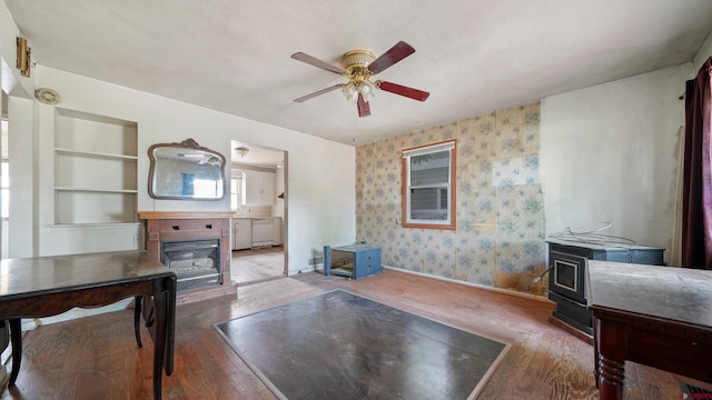 735 Teller Ave, Grand Junction, CO 81501 - living room featuring a wood stove, ceiling fan, hardwood / wood-style flooring, wallpapered walls, and built in shelves