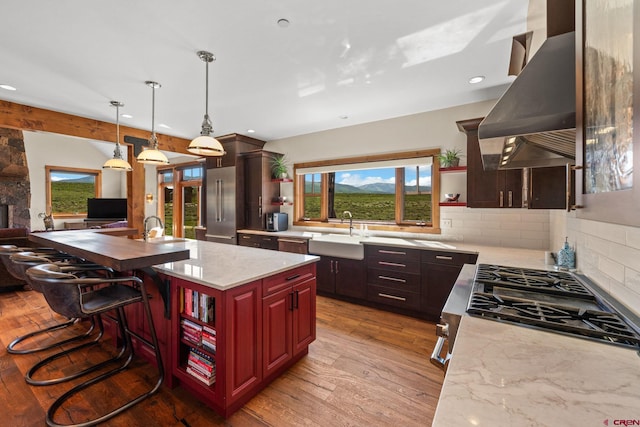322 Wapiti Ln, Crested Butte, CO 81224 - kitchen with open shelves, island range hood, light wood-style floors, tasteful backsplash, and a kitchen island with sink