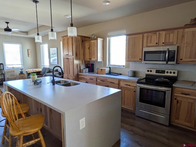 117 N Fork Ave, Paonia, CO 81428 - kitchen with appliances with stainless steel finishes, ceiling fan, a breakfast bar area, dark wood-type flooring, and a center island with sink