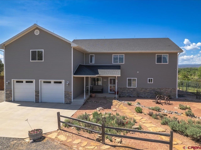 12689 6100th Rd, Montrose, CO 81401 - back of property featuring covered porch, stone siding, concrete driveway, and an attached garage