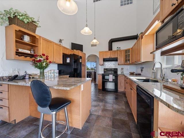 12689 6100th Rd, Montrose, CO 81401 - kitchen with black appliances, a towering ceiling, under cabinet range hood, a peninsula, and light stone countertops