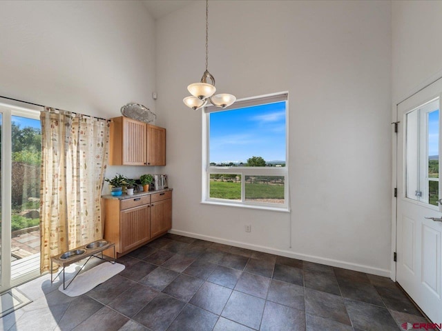 12689 6100th Rd, Montrose, CO 81401 - unfurnished dining area with high vaulted ceiling, healthy amount of natural light, a chandelier, and dark stone finish floors