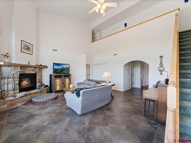 12689 6100th Rd, Montrose, CO 81401 - living room featuring arched walkways, a ceiling fan, stairs, a towering ceiling, and a fireplace