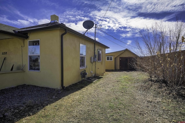 1132 Robinson Ave, Trinidad, CO 81082 - rear view of house featuring stucco siding, a shed, and a chimney