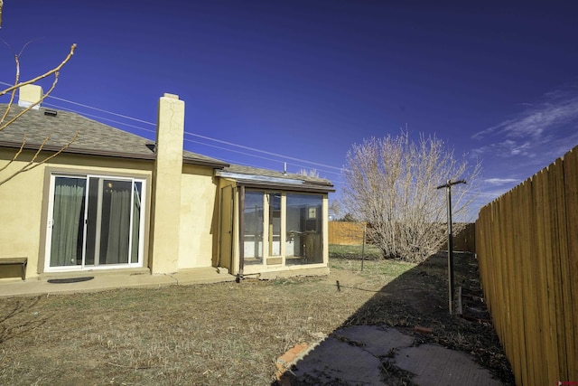 1132 Robinson Ave, Trinidad, CO 81082 - back of house featuring a fenced backyard, a sunroom, stucco siding, and a chimney