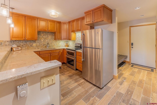 20 Hunter Hill Rd Unit 110, Mount Crested Butte, CO 81225 - kitchen with appliances with stainless steel finishes, light stone counters, backsplash, light wood finished floors, and pendant lighting