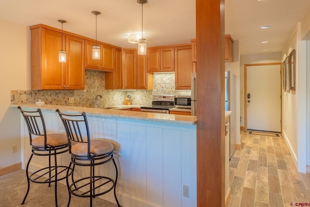 20 Hunter Hill Rd Unit 110, Mount Crested Butte, CO 81225 - kitchen with appliances with stainless steel finishes, a peninsula, backsplash, light wood-style flooring, and pendant lighting