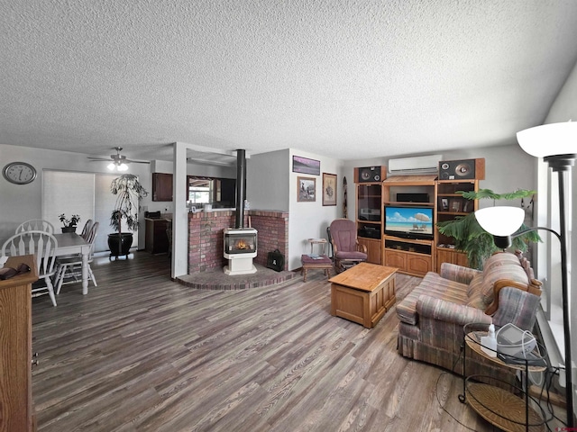 613 N Colorado St, Cortez, CO 81321 - living area featuring an AC wall unit, a wood stove, a textured ceiling, wood finished floors, and a ceiling fan