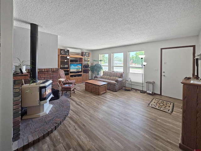 613 N Colorado St, Cortez, CO 81321 - living room with a wood stove, a textured ceiling, a wall mounted air conditioner, and wood finished floors