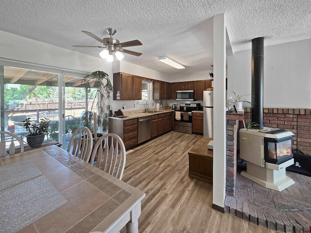 613 N Colorado St, Cortez, CO 81321 - kitchen with appliances with stainless steel finishes, a wood stove, ceiling fan, light wood-style floors, and light countertops