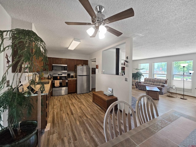 613 N Colorado St, Cortez, CO 81321 - kitchen featuring appliances with stainless steel finishes, light wood finished floors, a textured ceiling, open floor plan, and light countertops