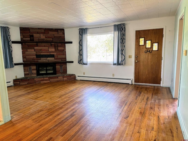 20114 Austin Rd, Austin, CO 81410 - unfurnished living room featuring a baseboard heating unit, wood finished floors, a stone fireplace, and baseboard heating