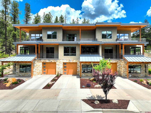 928 Twin Buttes Ave, Durango, CO 81301 - view of front of property with stone siding, a standing seam roof, a balcony, a garage, and stucco siding
