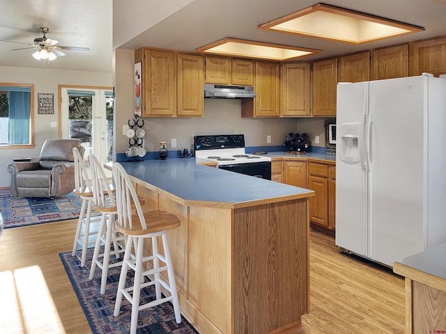 14245 Rd 21, Cortez, CO 81321 - kitchen with white fridge with ice dispenser, range with electric stovetop, under cabinet range hood, light wood-type flooring, and a peninsula