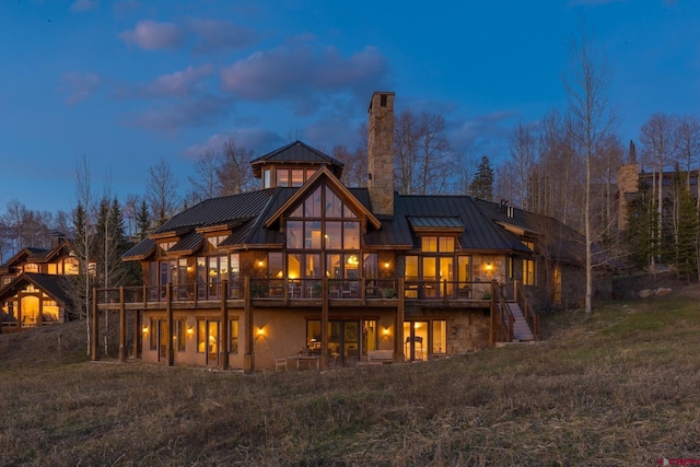 404 Benchmark Dr, Mountain Village, CO 81435 - back of house at dusk featuring a standing seam roof, stairs, a chimney, a metal roof, and a deck