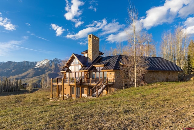 404 Benchmark Dr, Mountain Village, CO 81435 - back of house with a standing seam roof, stone siding, a chimney, a deck with mountain view, and a metal roof