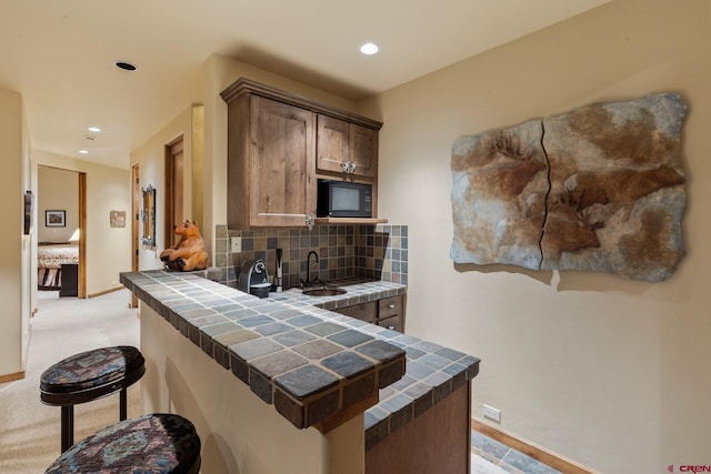 404 Benchmark Dr, Mountain Village, CO 81435 - kitchen featuring tile counters, black microwave, a breakfast bar, backsplash, and recessed lighting